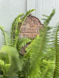 A close-up of a handcrafted garden sign with intricate details surrounded by lush greenery