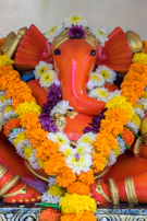A vibrant Ganesh idol painted with natural dyes, surrounded by fresh marigold flowers.