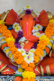 A vibrant Ganesh idol painted with natural dyes, surrounded by fresh marigold flowers.