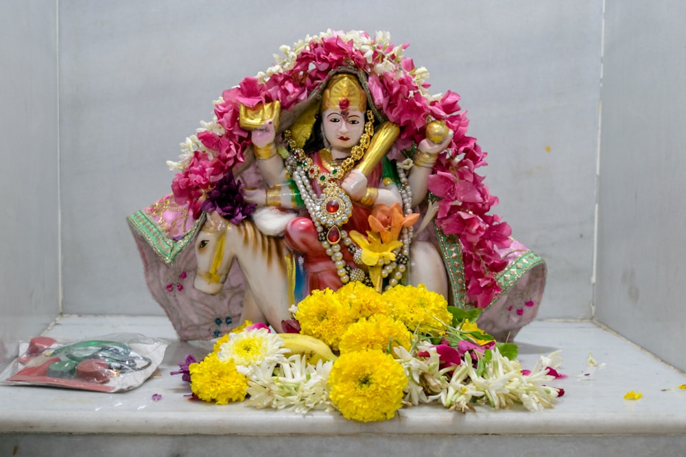 a statue of a hindu god surrounded by flowers