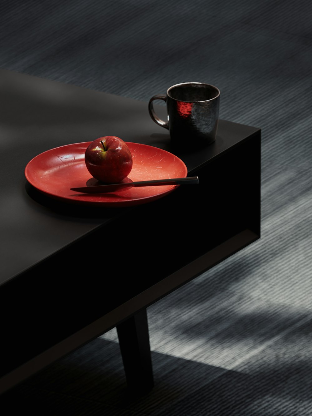 a red plate with an apple on it next to a cup