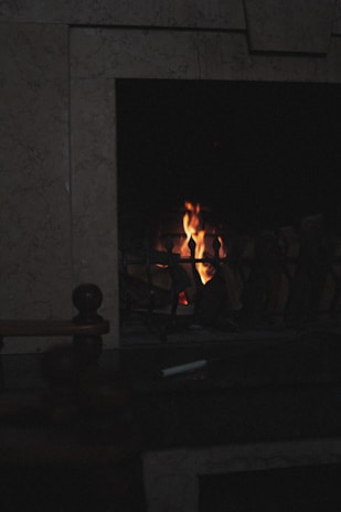 A cozy hearth glowing softly in a dimly lit room, symbolizing warmth and comfort.