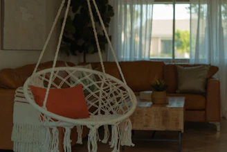 A cozy living room softly illuminated by a round ceiling light and a bohemian macrame lamp.