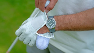 Close-up of a golfer analyzing data on a digital device with a focused expression.