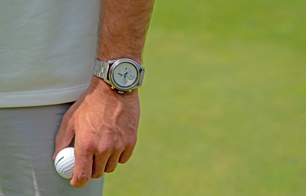 um close up de uma pessoa segurando uma bola de golfe