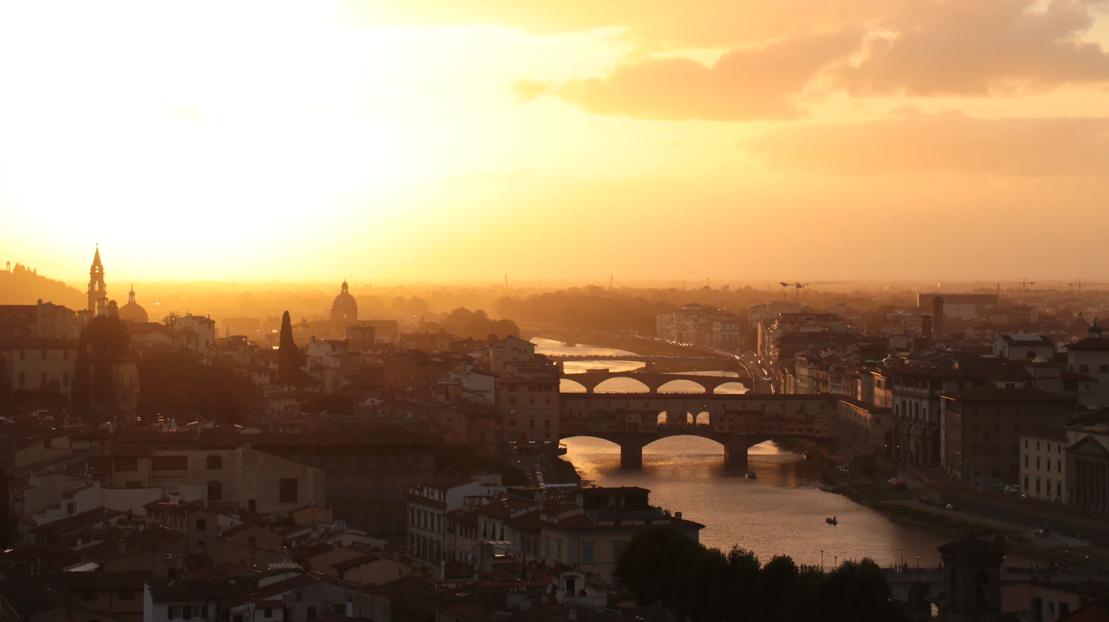 Sun setting over the Arno River and the bridges of Florence, a common stop on an Italy itinerary