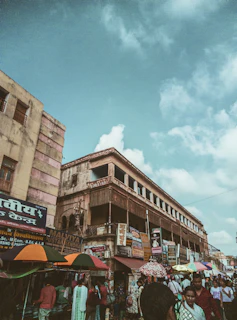 a group of people walking around a market under a cloudy sky