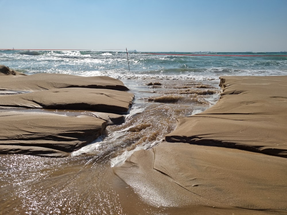 a sandy beach with waves coming in and out of the water