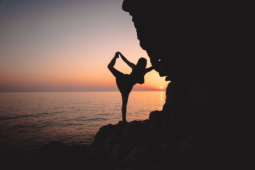 a person doing a yoga pose on a cliff near the ocean