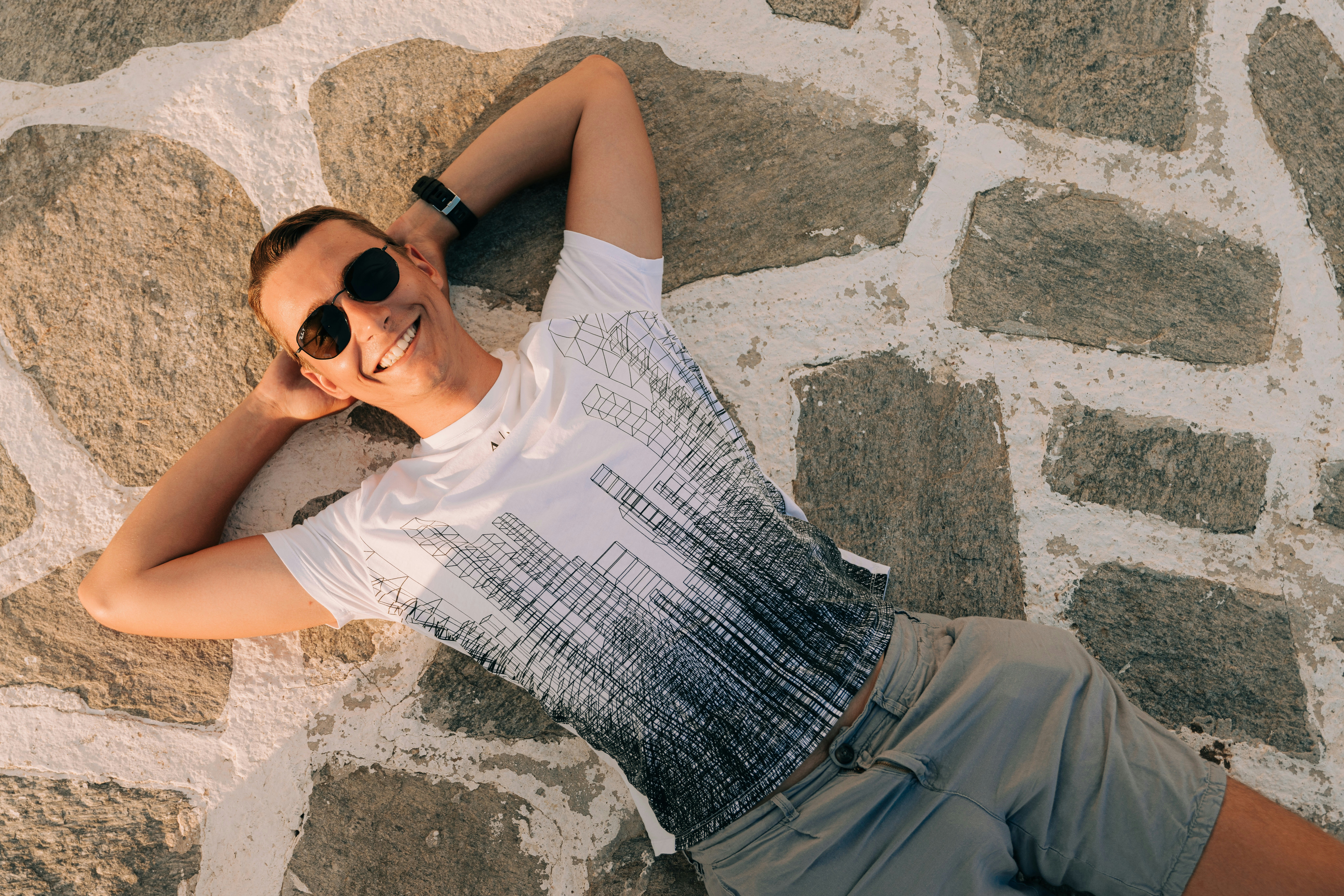 a man laying on the ground wearing sunglasses