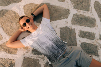 a man laying on the ground wearing sunglasses