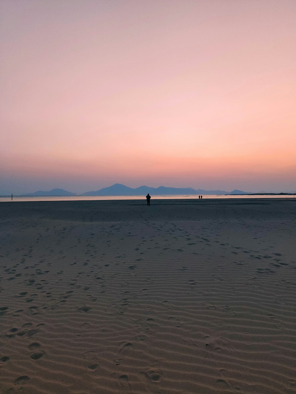 a person walking on a beach at sunset