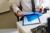 a man in a white shirt and tie holding a folder