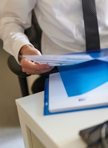 a man in a white shirt and tie holding a folder