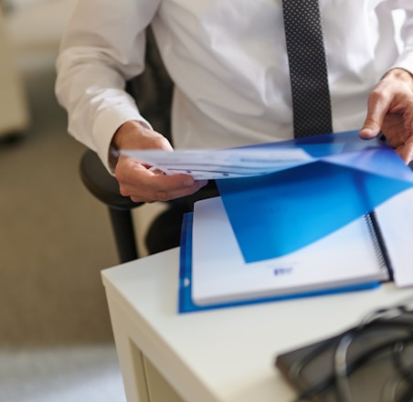 a man in a white shirt and tie holding a folder