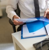 a man in a white shirt and tie holding a folder