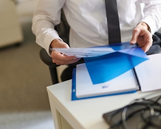 a man in a white shirt and tie holding a folder