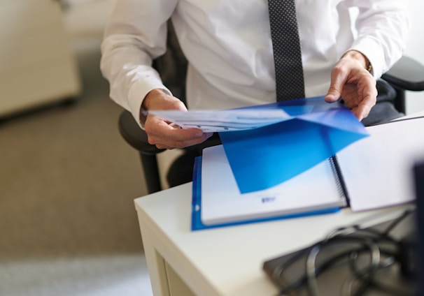 a man in a white shirt and tie holding a folder