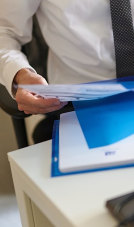 a man in a white shirt and tie holding a folder