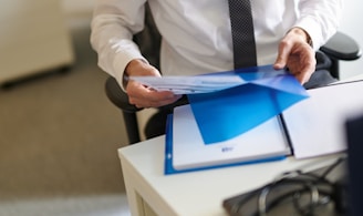 a man in a white shirt and tie holding a folder