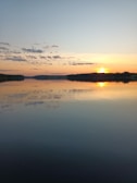 A serene sunset over a calm lake reflecting soft pastel colors.