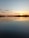 A peaceful sunset over a quiet lake surrounded by trees.