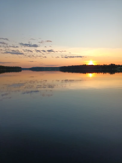 A serene sunset over a quiet lake reflecting soft pastel colors.