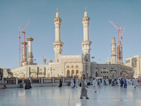 Construction workers laying the foundation of Masjid Al Barakah under a bright sky.