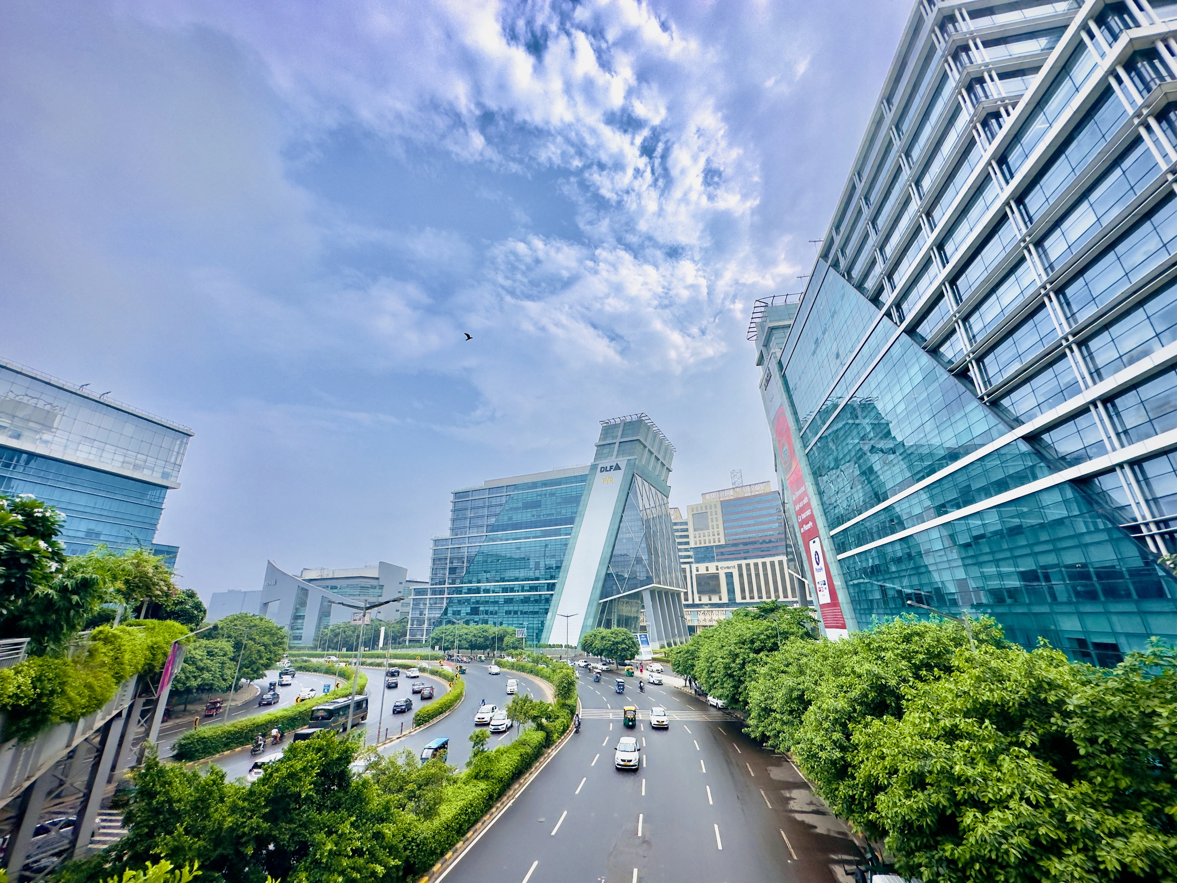 Glass office towers and a tree-lined road in Gurugram's business district