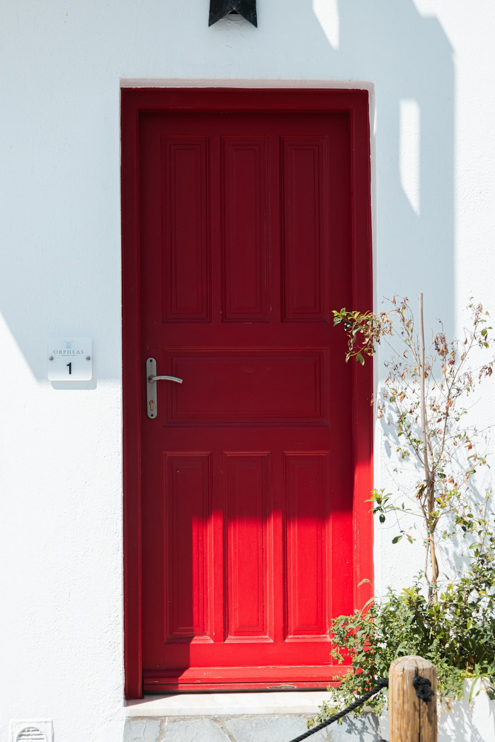 a red front door with a clock on the side of it