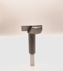 A metal tool with a cylindrical handle and a sharp, angular cutting head is positioned vertically against a plain, light background. The tool appears to be designed for precision cutting or boring tasks.