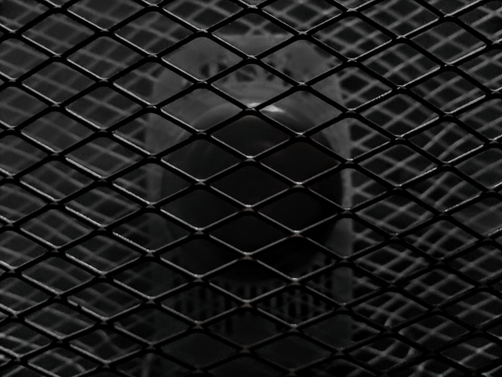 a black and white photo of a clock tower through a chain link fence