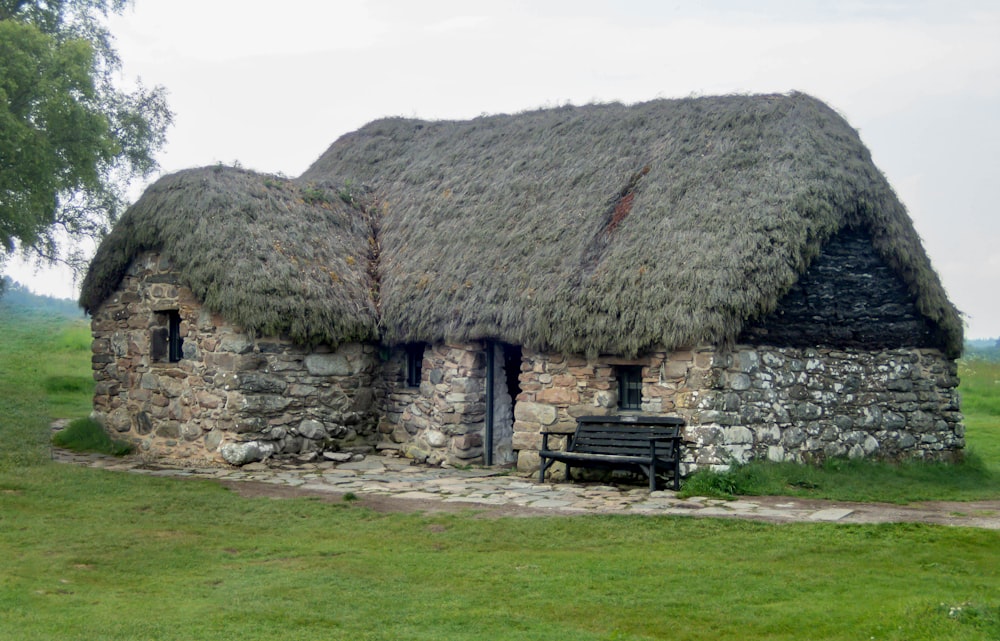 a stone house with a thatched roof and a bench