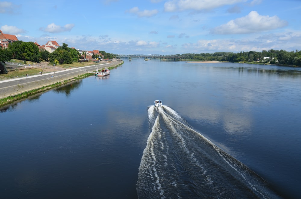 a boat traveling down a river next to a lush green hillside