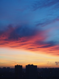 a city skyline at sunset with a red and blue sky