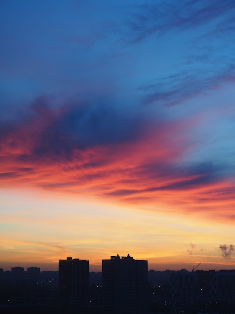 a city skyline at sunset with a red and blue sky