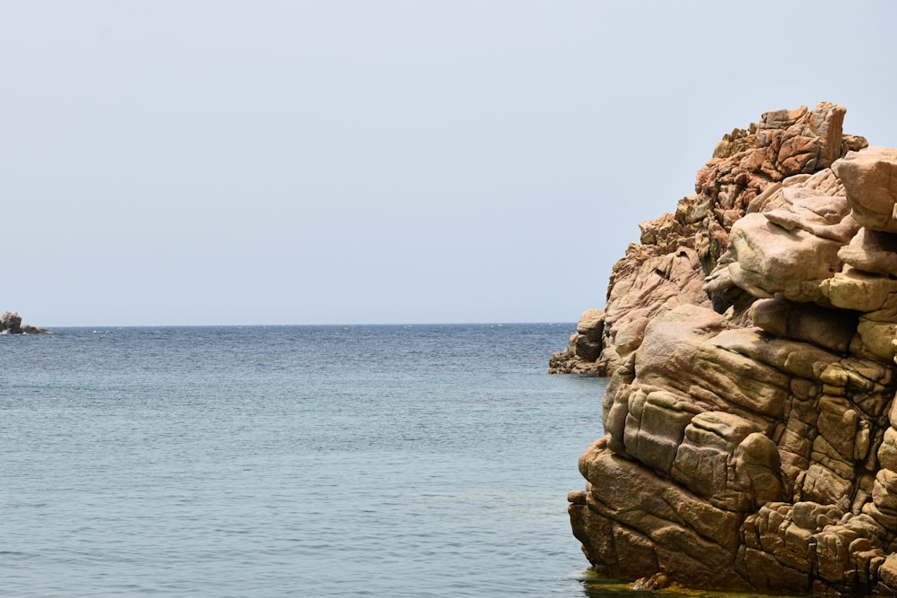 a boat is in the water near a rocky outcropping