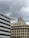Several buildings with industrial and commercial designs stand under an overcast sky. An architectural structure features numerous antennas and communication devices on its rooftop.