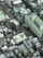 The aerial view captures a densely packed urban area with various multi-story buildings. The architecture includes both residential and commercial structures with flat rooftops. Some rooftops have solar panels, and one prominently features an 'e-tax' logo. The scene is dominated by concrete and asphalt but is interspersed with patches of greenery.