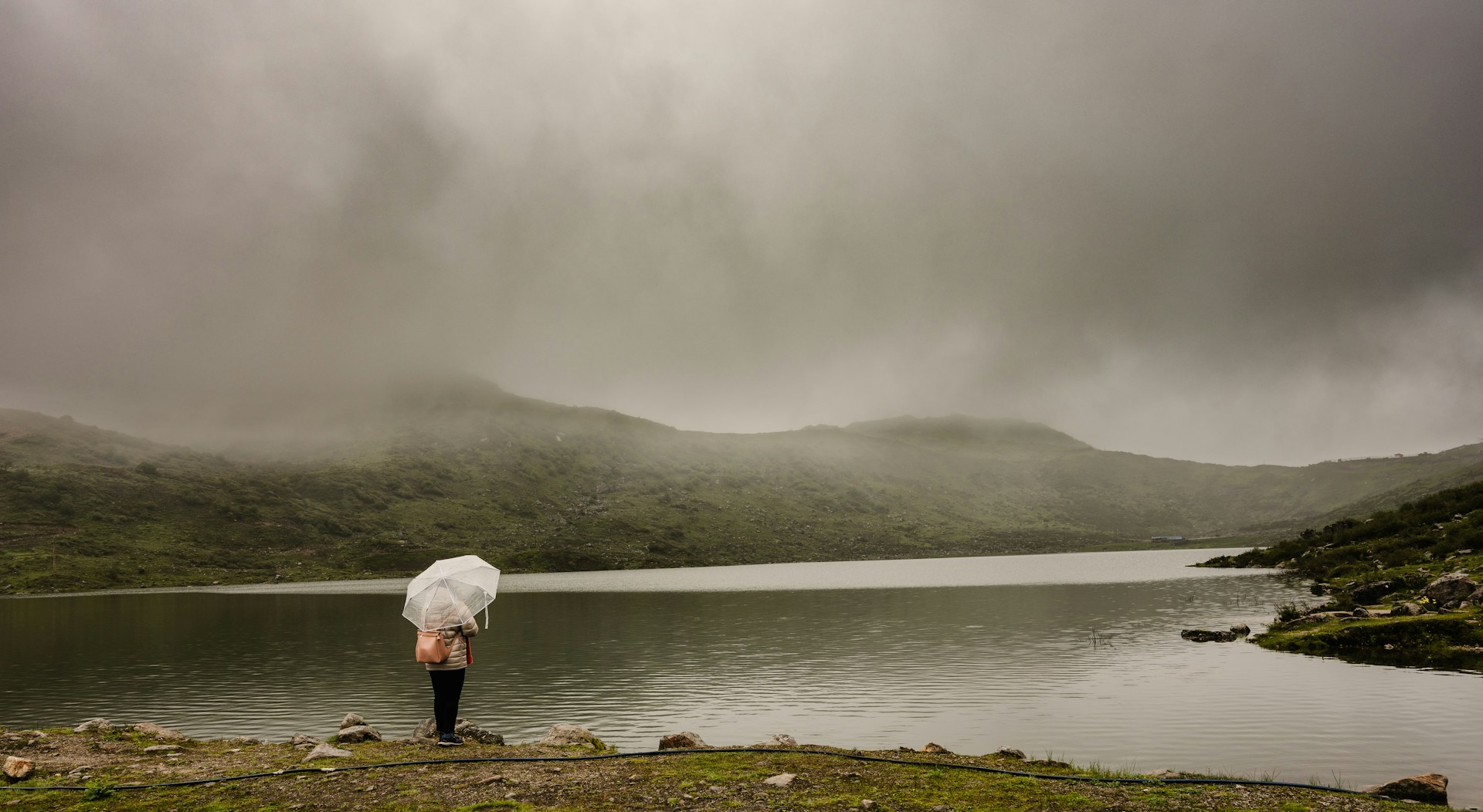 a person with an umbrella standing by a lake