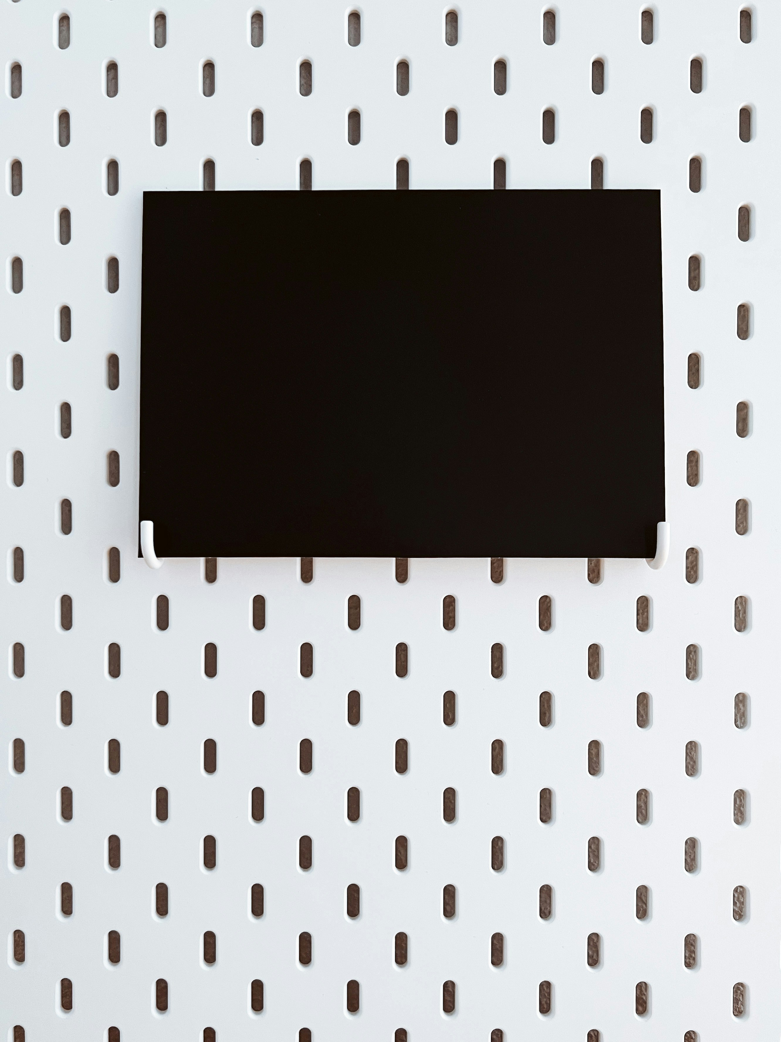 a piece of black paper sitting on top of a white wall