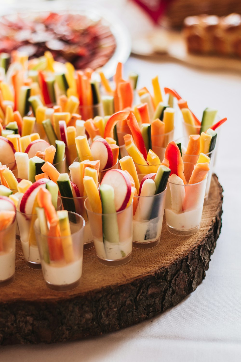 a wooden platter filled with small cups filled with veggies