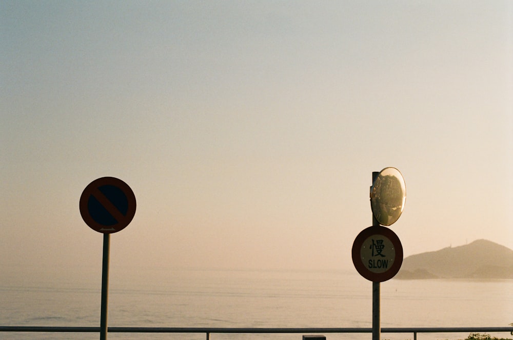 a row of street signs next to a body of water