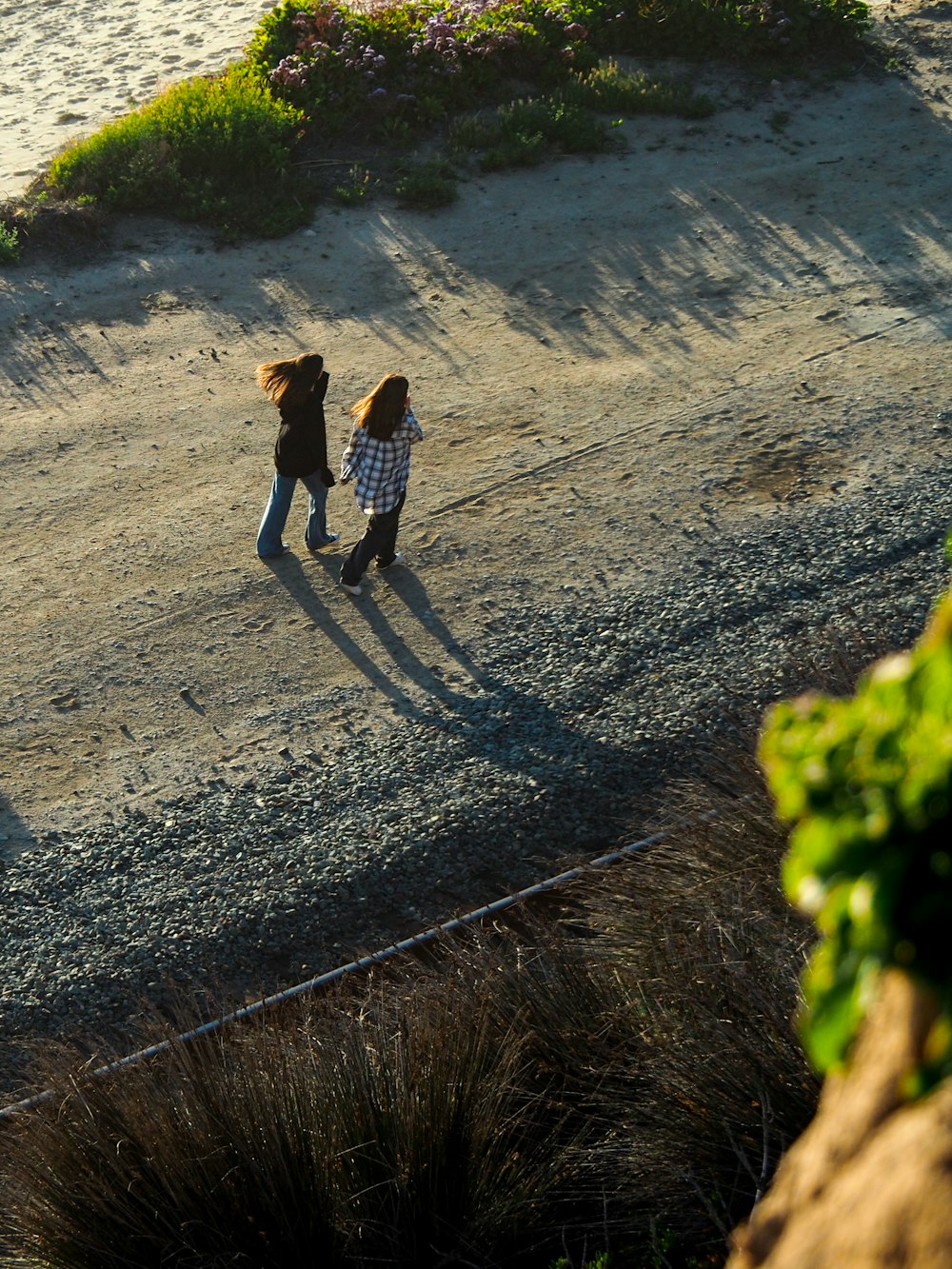 a couple of people walking down a dirt road