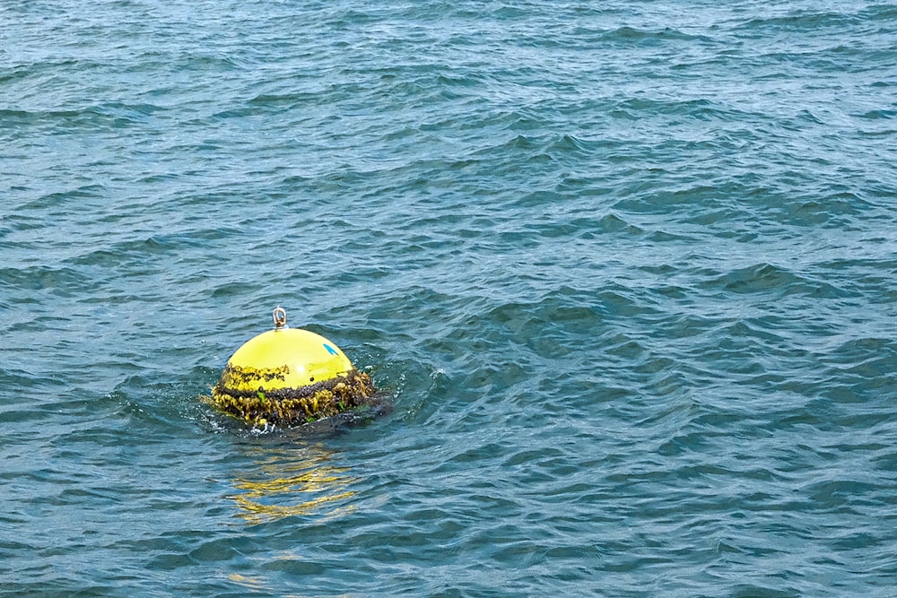 a yellow buoy floating in the middle of a body of water