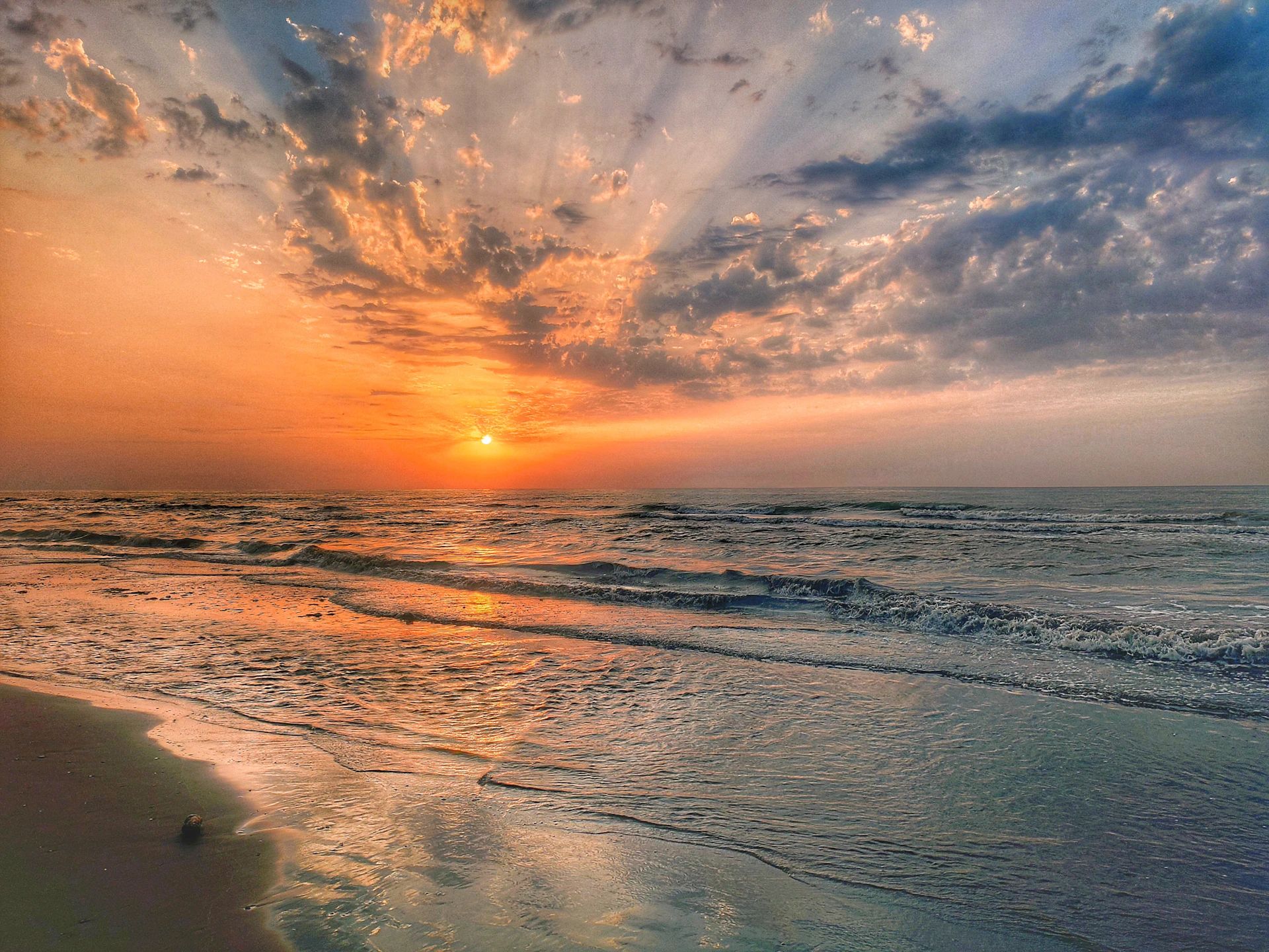 A stunning sunset over Radhanagar Beach with vibrant orange and pink hues reflecting on the calm sea.
