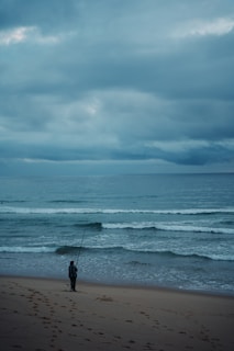 a man standing on top of a sandy beach next to the ocean