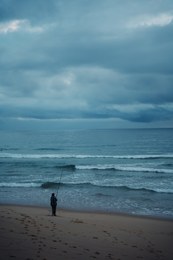 a man standing on top of a sandy beach next to the ocean