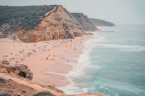 A scenic beach view of Praia da Pipa with tourists enjoying the sun and ocean.