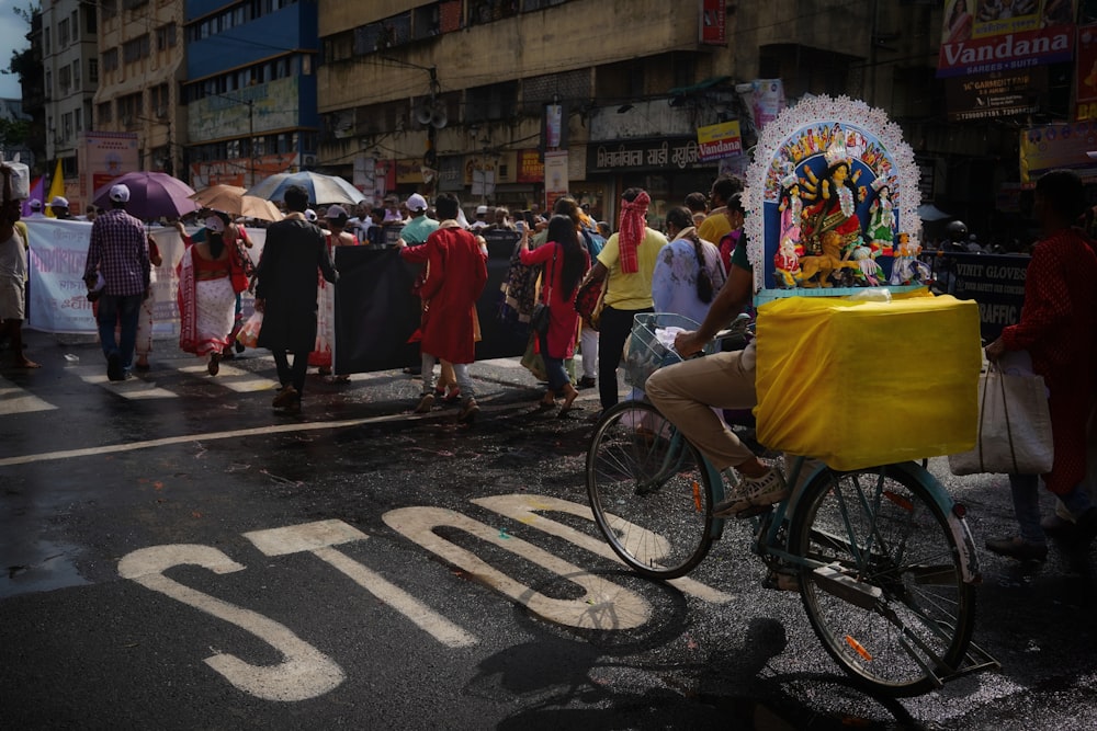 a man riding a bike down a street next to a crowd of people